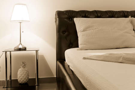 bedroom with double bed and table lamp, sepia toning