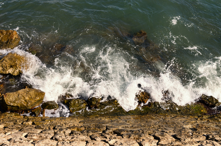 Waves breaking on stone coast at sunset with warm colorsの写真素材