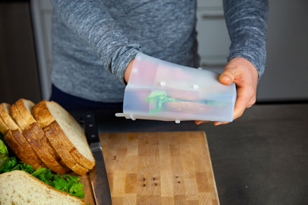 A women prepares lunch and puts a sandwich into a food-grade silicone bag as part of a zero-waste lifestyle to replace plastic bagsの写真素材
