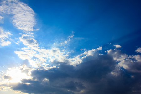 Bright sun rays through the white clouds with deep blue sky background, creating beautiful scenery の写真素材
