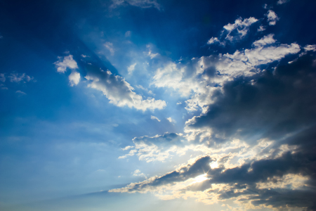 Bright sun rays through the dark clouds with deep blue sky background, creating beautiful scenery の写真素材