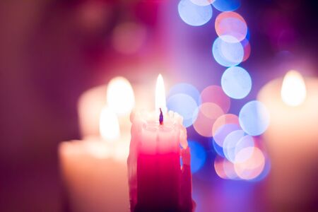 Candle lights on the background of colorful bokeh. Christmas and New Year.の写真素材