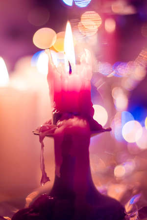 Candle burns on a stand against the bright colorful bokeh. Christmas and New Year.の写真素材