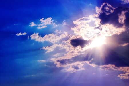 Bright sun rays through the clouds with deep blue sky background, creating beautiful scenery.の写真素材
