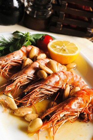 Large cooked shrimp on a platter with lemon green beans and tomatoes in a restaurant.の写真素材