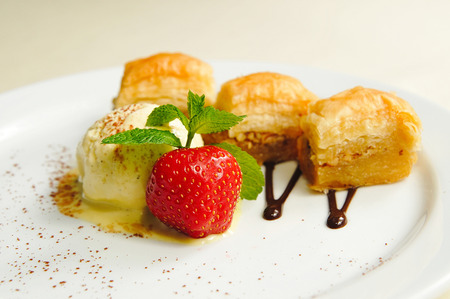 Melted ice cream under the slice of cinnamon with fresh strawberries and baklava with icecream strawberries and mint poured chocolate strawberry sweet baklava chocolate cream sprinkled with cinnamonの写真素材