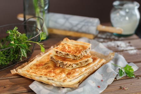 Potato Square Pie with parsley and greens. A square piece of meat pie on a rectangular meat pie on a...