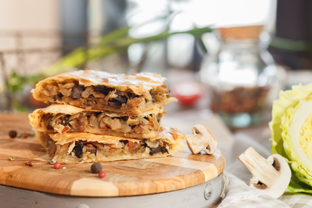 Puff pastry Pie with stewed cabbage and dried mushrooms and green cabbage and fresh champignonsの写真素材