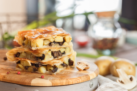 Cake with fried champignons potatoes pepper on a blurry kitchen backgroundの写真素材