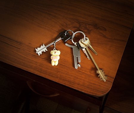 A bunch of keys with a soccer player and a teddy bear trinketsの写真素材