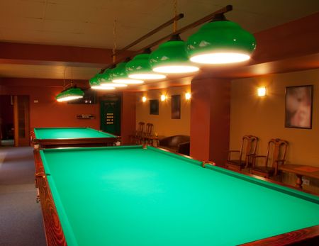 Interior of a club having billiard tables illuminated with lights