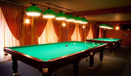 Interior of a club having billiard tables illuminated with lights