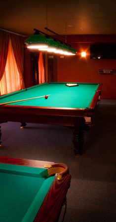 Interior of a club having billiard tables illuminated with lights