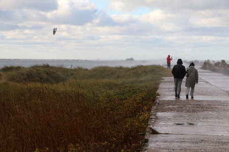 Stormy Baltic Sea with port piers, people and kiteboarder in the distance, Europeの写真素材