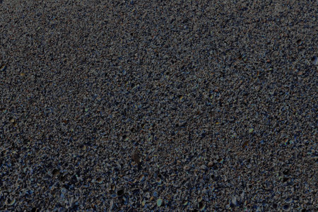 Close-up of a surface covered with small pebbles and stones of varied sizes and colors, forming a...