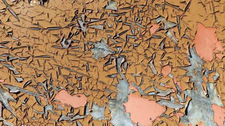 Close-up of peeling paint in brown and pink shades, revealing a gray underlayer. Rough, cracked...