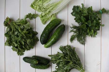 cucumbers and greens on a white tableの写真素材