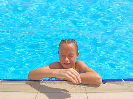 A girl at the side in a pool with clean clear water. The girl closed her eyes.の写真素材