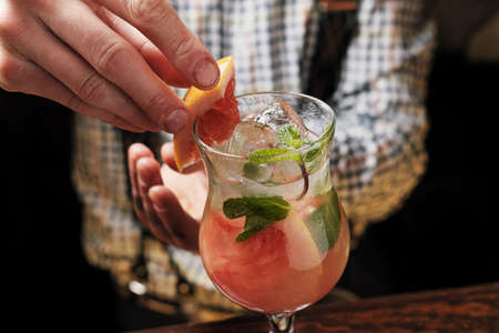 Bartender finished decorating his cocktail with mint and orange sliceの写真素材