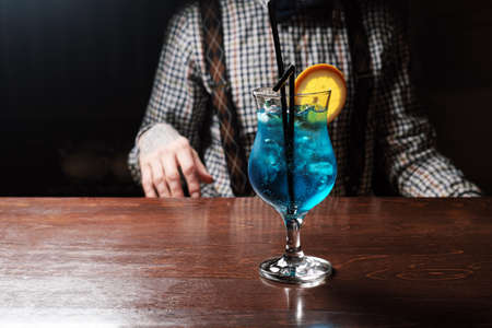 Blue curacao cocktail with lime, ice and mint in martini glasses on wooden backgroundの写真素材