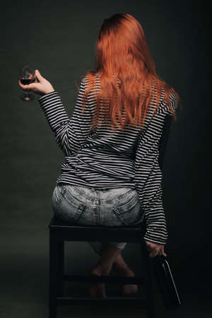 beautifu girl sitting on bar chair and holding bottleの写真素材