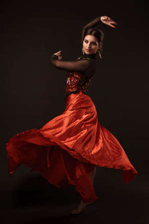 Beautiful belly dancer perfoming exotic dance in red flutter dress artの写真素材