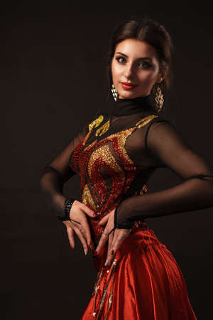 Beautiful belly dancer perfoming exotic dance in red flutter dress artの写真素材