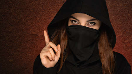 Beautiful Arabian woman portrait traditional costume indoors. Young Hindu woman. Close-up portrait of beauty model with bright makeup who hiding her face behind transparent veil standing over dark artの写真素材