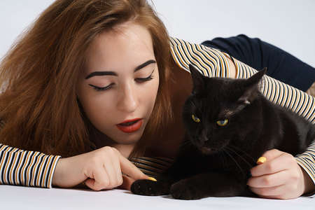 girl with black mischievous cat on white. almost isolate artの写真素材
