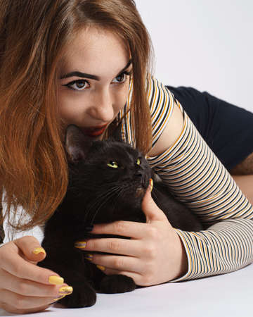 girl with black mischievous cat on white. almost isolate artの写真素材