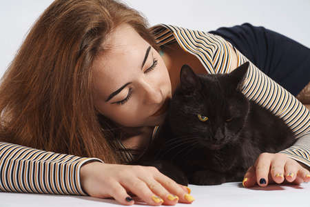 girl with black mischievous cat on white. almost isolate artの写真素材