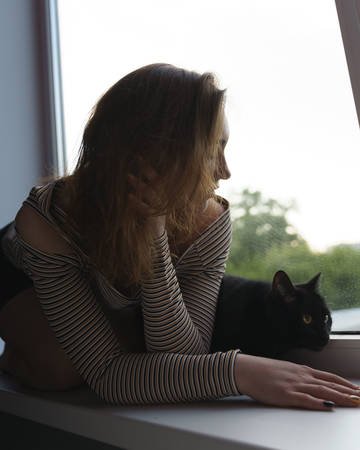 girl in a skirt and a cat are sitting on the window on the street evening artの写真素材