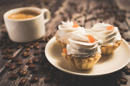 A cup of coffee and cake baskets with brown cream and berry.の写真素材