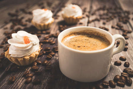 A cup of coffee and cake baskets with brown cream and berry.の写真素材