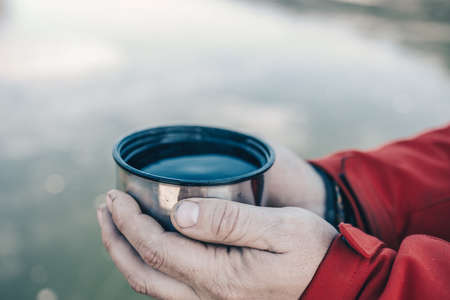 Pours hot tasty tea from a flask in the winter into the cold.の写真素材