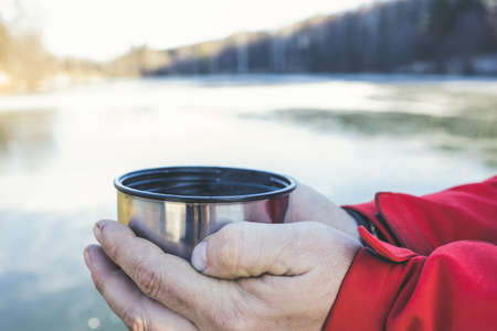 Pours hot tasty tea from a flask  in the winter into the cold.