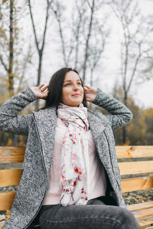 Girl in autumn sits on a benchの写真素材