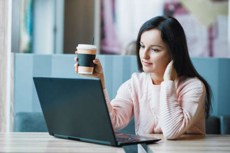 Freelancer girl at a laptop with coffee thinksの写真素材