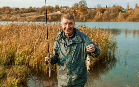 Elderly fisherman with red hair caught a good fish perch.の写真素材