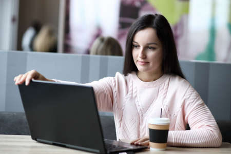 Girl in a cafe opens a laptop for workの写真素材