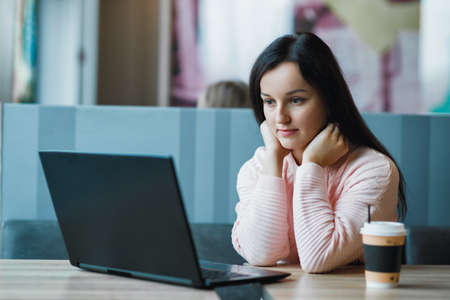 Girl freelancer at a laptop with coffee got lost and sadの写真素材