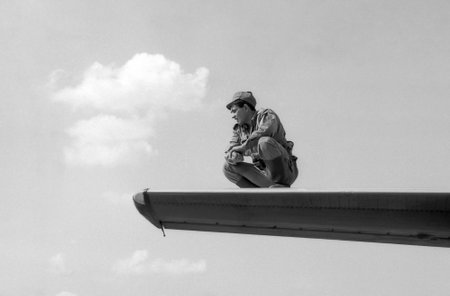 MOSCOW REGION, RUSSIA - CIRCA 1993: A soldier sitting on the wing of a military transport plane An-24. Film scan. Large grain, circa 1993 のeditorial素材