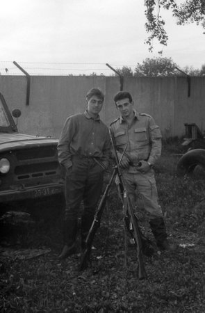 MOSCOW REGION, RUSSIA - CIRCA 1993: Two soldiers with weapons near the army SUV UAZ-469. Film scan. Large grain, circa 1993 のeditorial素材