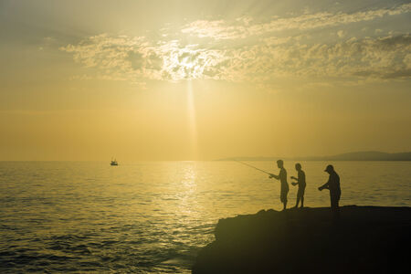 Silhouette of fishermen fishing on the Mediterranean Sea, Turkeyの写真素材