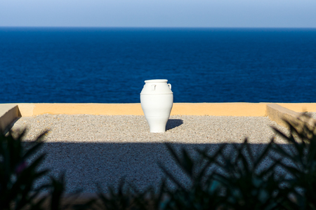 Typical view of the Mediterranean region. Decorative white amphora on a background of blue sky and sea.の写真素材