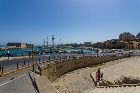 HERAKLION, GREECE - JULY 16, 2016: Crete. Moored fishing boats in the seaport. In the background an old Venetian fortress and the city's neighborhoods.のeditorial素材