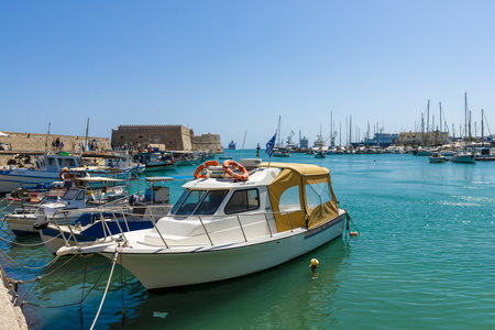 HERAKLION, GREECE - JULY 16, 2016: Crete. Moored fishing boats in the seaport. In the background an old Venetian fortress.のeditorial素材