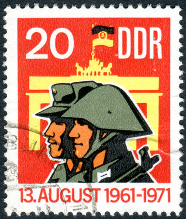 GERMANY - CIRCA 1971: A stamp printed in Germany (GDR), dedicated to 10 years of Berlin Wall, shows the Militiaman, Soldier and Brandenburg Gate, circa 1971のeditorial素材