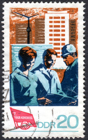 GERMANY - CIRCA 1968: A stamp printed in Germany (GDR), dedicated to 7th Congress of the Free German Trade Unions, shows the Young workers, new apartment buildings and Congress emblem, circa 1968のeditorial素材