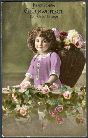 GERMANY - CIRCA 1915: A greeting postcard printed in Germany, shows a girl with a basket of flowers. The inscription in German: Happy birthday, circa 1915のeditorial素材